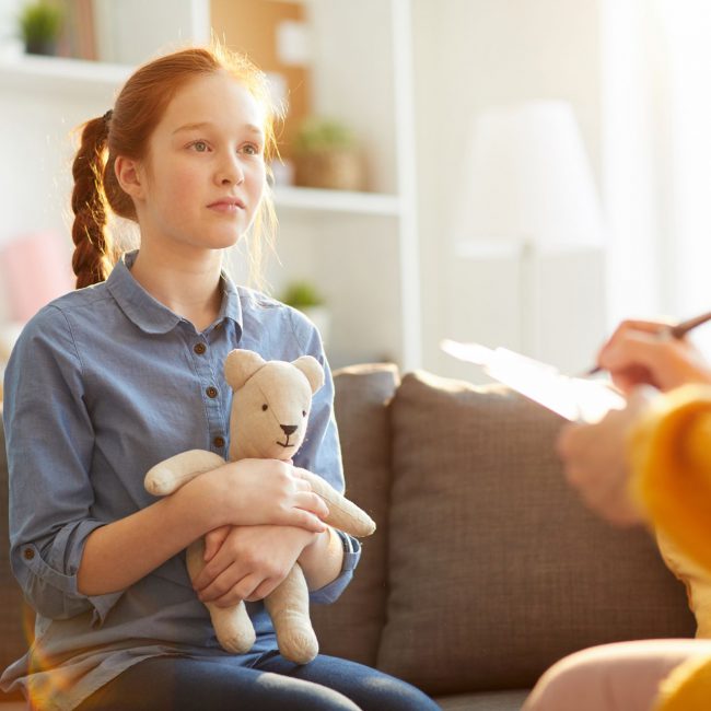 Teenager in Therapy Session Portrait of red haired teenage girl listening to psychologist during therapy session on youth issues, copy space