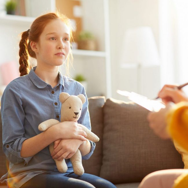 Portrait of red haired teenage girl listening to psychologist during therapy session on youth issues, copy space